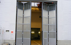 Skládací vrata o rozměru 5 x 6,5m s prosklením a el. pohonem